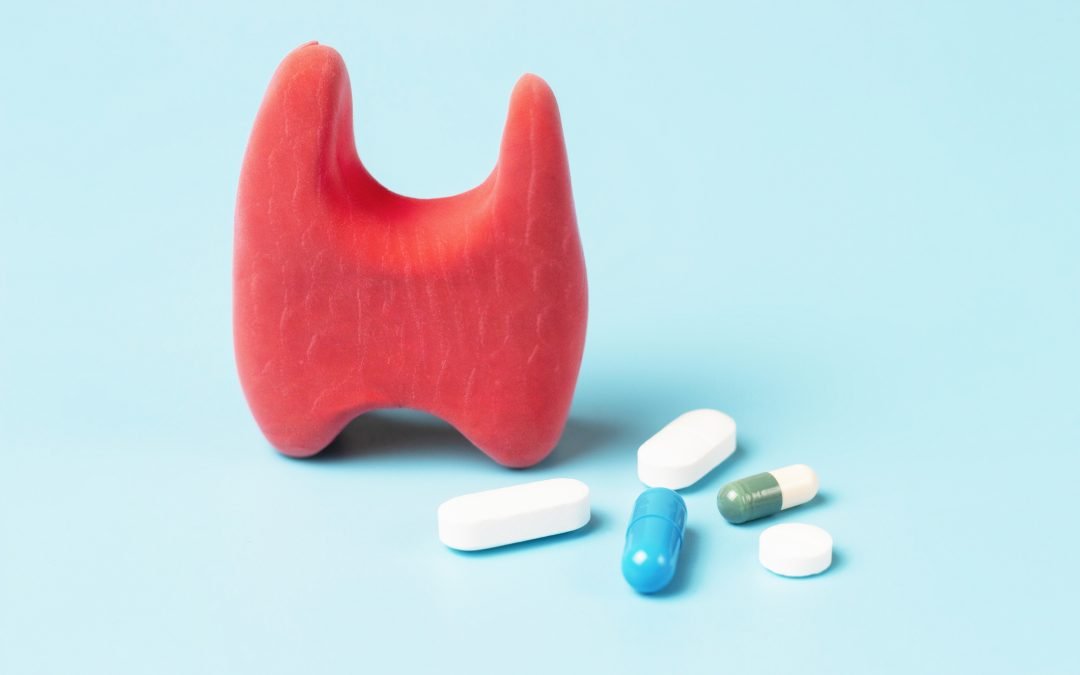 Thyroid model and pills on a blue background front view, copy space