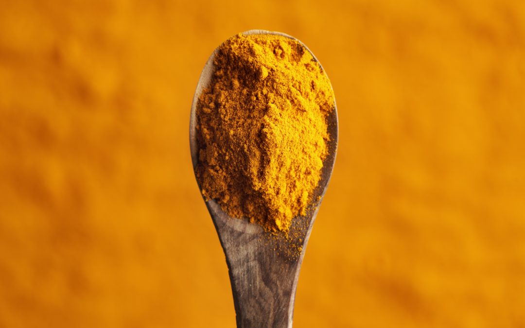 Turmeric root powder on a wooden spoon, top view